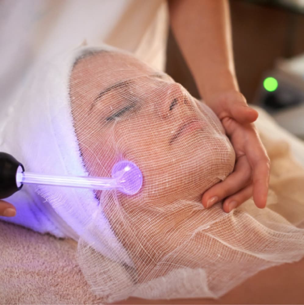 Kaylee performing a high-frequency facial treatment